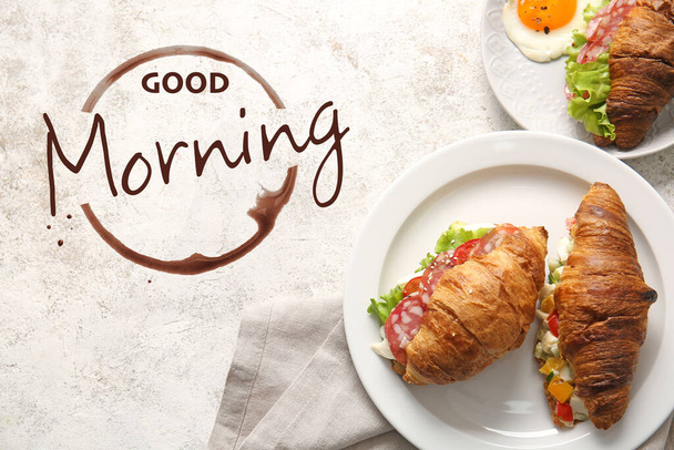 Plates with delicious croissant sandwiches and text GOOD MORNING on light background, top view - Fotoğraf, Görsel