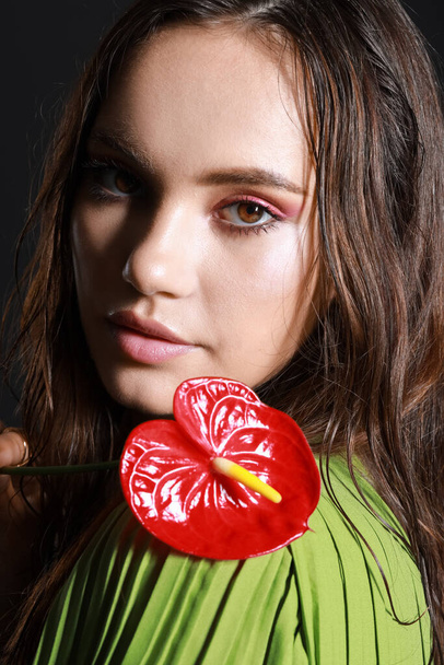 Portrait of young woman with wet hair holding anthurium flower, closeup - Photo, Image