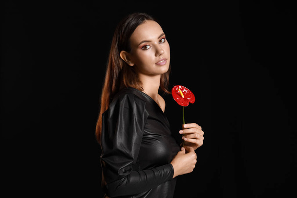 Portret modnej kobiety z pięknym kwiatem anthurium na czarnym tle - Zdjęcie, obraz