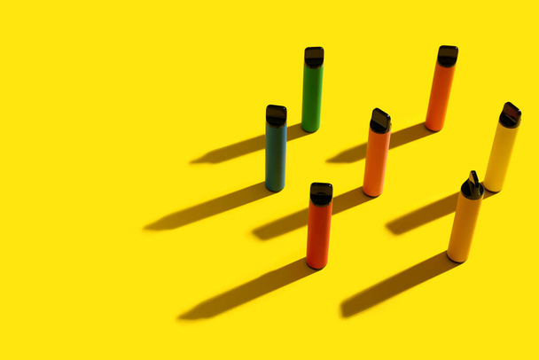 Disposable electronic cigarettes on yellow background - Foto, Imagen