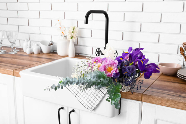 Víznyelő gyönyörű virágokkal a konyhán, közelről - Fotó, kép