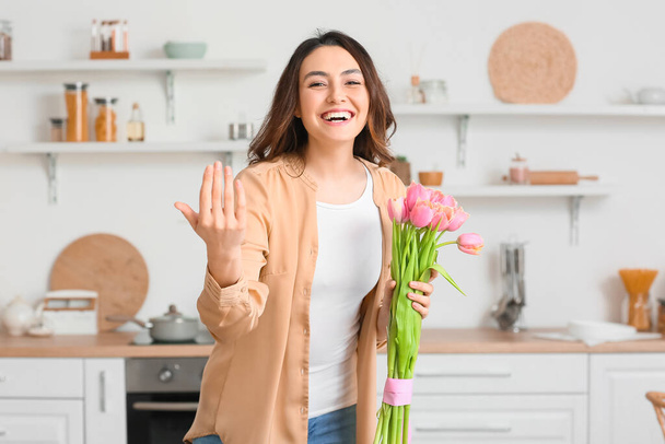 Young woman with bouquet of flowers inviting viewer at home - Photo, Image