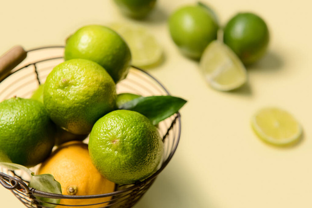 Basket with ripe limes and lemon on color background, closeup - Foto, Imagen
