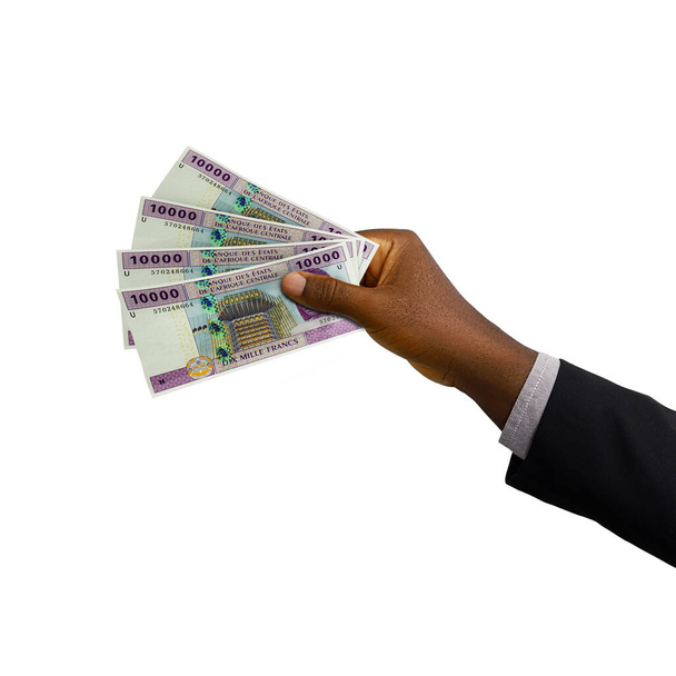 Black hand with suit holding 3D rendered 10000 Central African CFA franc notes isolated on white background - Fotó, kép