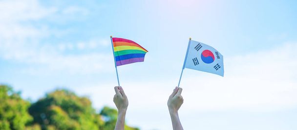 ruce ukazující vlajku LGBTQ Rainbow a Korea na přírodním pozadí. Podpora lesbických, gayů, bisexuálů, transsexuálů a homosexuálů komunita a hrdost měsíční koncept - Fotografie, Obrázek