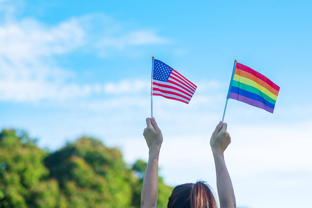 hands showing LGBTQ Rainbow and America flag on nature background. Support Lesbian, Gay, Bisexual, Transgender and Queer community and Pride month concept - Fotografie, Obrázek