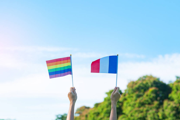 hands showing LGBTQ Rainbow and France flag on nature background. Support Lesbian, Gay, Bisexual, Transgender and Queer community and Pride month concept - Fotografie, Obrázek