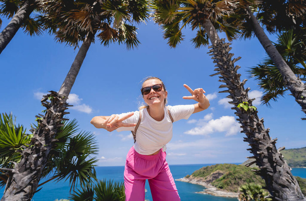 Yaz tatilindeki genç gezgin kadın güzel palmiyeler ve deniz manzaralarıyla - Fotoğraf, Görsel
