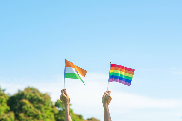 ruce ukazující vlajku LGBTQ Rainbow a Indie na přírodním pozadí. Podpora lesbických, gayů, bisexuálů, transsexuálů a homosexuálů komunita a hrdost měsíční koncept - Fotografie, Obrázek