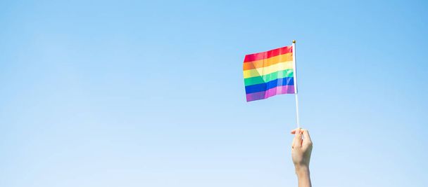 руки, показывающие флаг ЛГБТК Радуга на фоне природы. Support Lesbian, Gay, Bisexual, Transgender and Queer community and Pride month concept - Фото, изображение