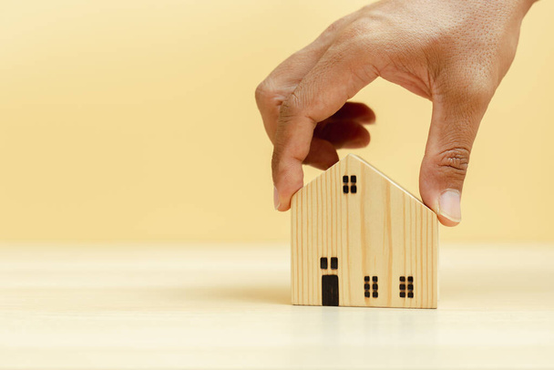 Концепція власності та інвестицій. рука тримає дерев'яну модель будинку, майновий бізнес фінансовий успіх
. - Фото, зображення