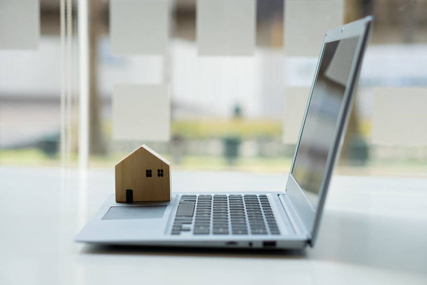 Small wooden house real estate idea placed on a laptop. - Foto, Bild