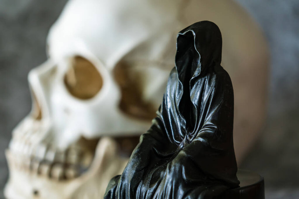 A statue of a grim reaper sitting and skull  background. - Valokuva, kuva