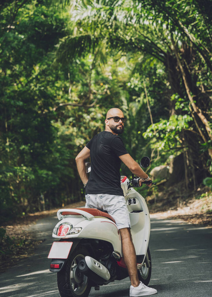 Stylish young man and his motorbike on the road in the jungle - Zdjęcie, obraz