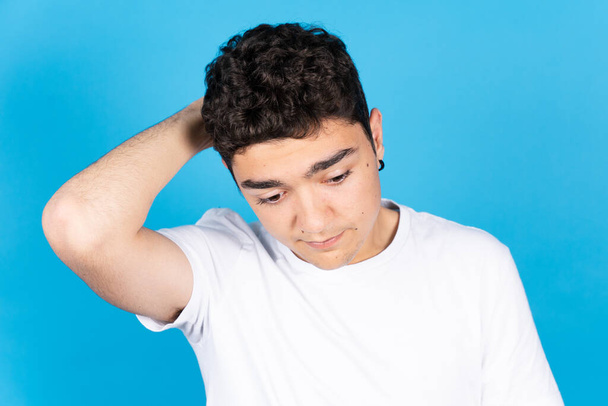 Ανησυχεί σκοτεινό ισπανόφωνο έφηβο αγόρι απομονωμένο σε μπλε φόντο - Φωτογραφία, εικόνα