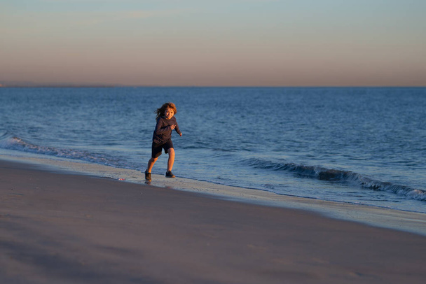 Little boy child running along ocean. Kid runs on sand beach. Summer vacation with child. - Foto, Bild