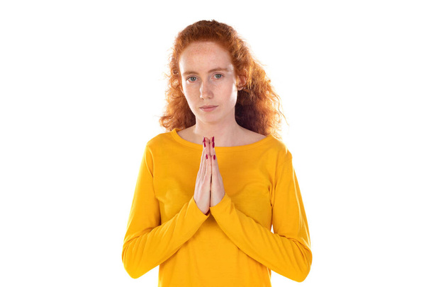 Aufrichtige rothaarige Frau hält Hände zusammen und betet in Pose vor weißem Hintergrund - Foto, Bild