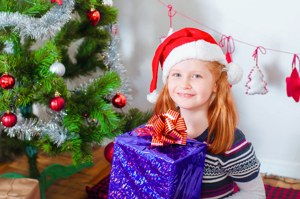 Little girl near the Christmas tree with gifts - Foto, Imagem