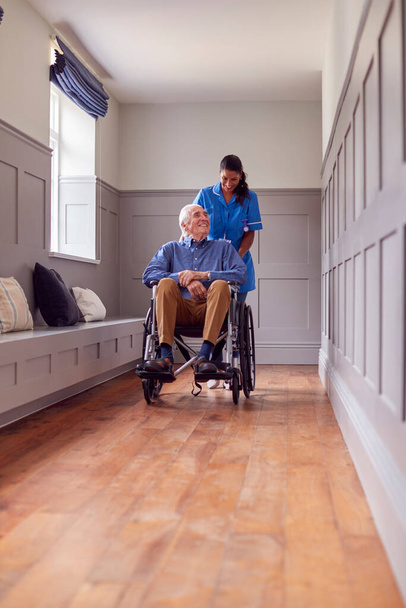 Senior Man At Home Being Pushed In Wheelchair By Female Care Worker In Uniform - Fotoğraf, Görsel