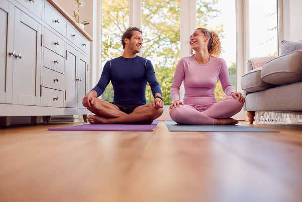 Couple Sitting On Mats At Home Doing Yoga Exercises Together - Fotografie, Obrázek