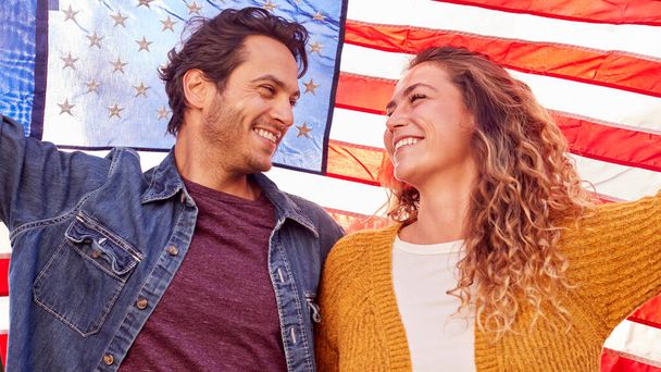 Portrait Of Patriotic American Couple Outdoors Holding Stars And Stripes Flag - Фото, изображение