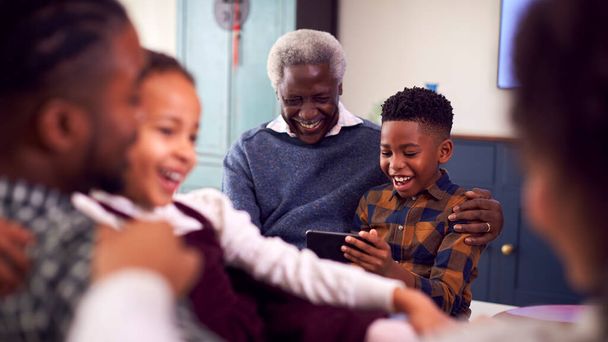 Grandfather With Grandchildren Playing Game On Mobile Phone At Home - Photo, image