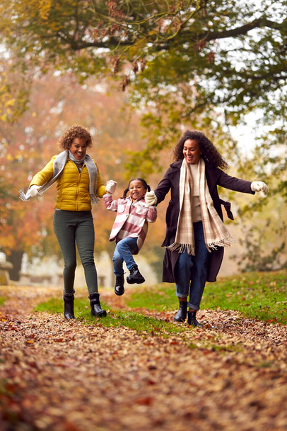 Multi-Generation Female Family Swinging Granddaughter On Walk Through Autumn Countryside Together - Foto, imagen