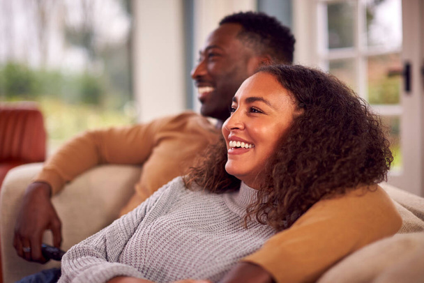 Smiling Couple Sitting On Sofa At Home Watching TV Together - Valokuva, kuva