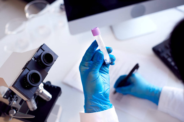 Primer plano del trabajador de laboratorio que conduce la investigación usando el tubo de sujeción del microscopio con la prueba de PCR Swab - Foto, Imagen