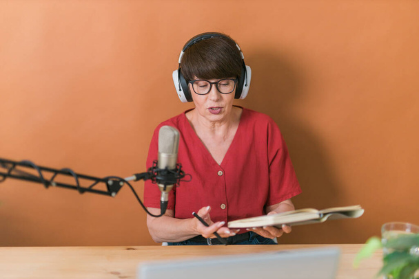 Портрет зрелой женщины в наушниках и беседах на онлайн радиостанции - подкаст и трансляция концепции - Фото, изображение