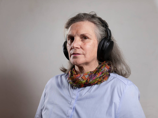 Portret van een volwassen vrouw luisterend naar muziek met haar koptelefoon tijdens zijn vrije tijd - Foto, afbeelding