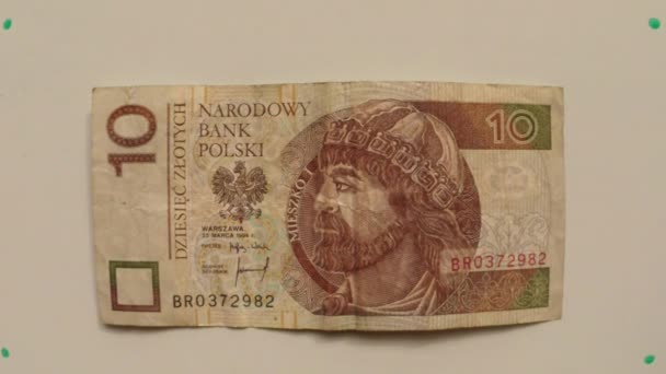 Papier monnaie 10 zloty, Pologne en 1994 sur une table blanche retourné une main de près
 - Séquence, vidéo