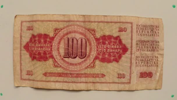 papierowe pieniądze 100 dinarów Banku Narodowego Jugosławii w 1986 na stół biały odwrócenie rękę z bliska - Materiał filmowy, wideo