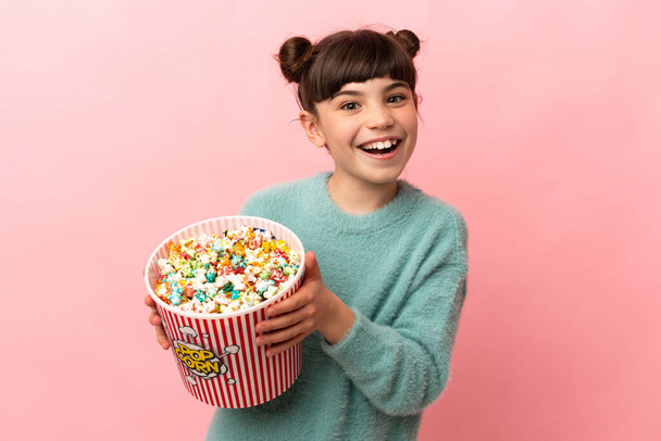 Piccola ragazza caucasica isolata su sfondo rosa con un grande secchio di popcorn - Foto, immagini