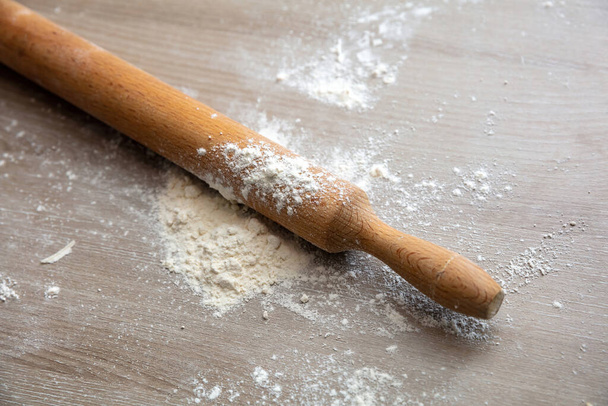 Rolling pin, wooden dough roller and flour on wood, Homemade dough and pastry preparation on kitchen table close up view, copy space - Zdjęcie, obraz