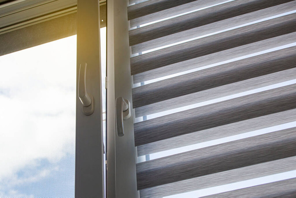 una ventana de plástico con una persiana enrollable y una mosquitera contra un cielo azul - Foto, imagen