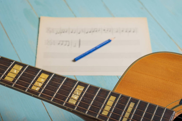 Music recording scene with guitar, music sheet and pencil on wooden table - Photo, image