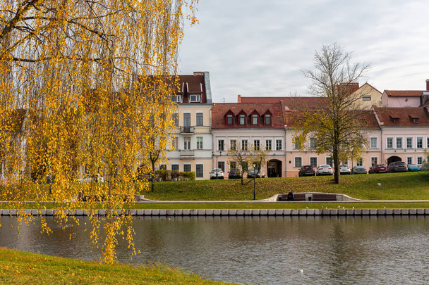 Minsk, Belarus 'taki Trinity Banliyösü, Upper City Minsk' in en eski bölgesinde, sonbaharda Svislach Nehri kıyısında turuncu sonbahar yapraklarıyla eski renkli geleneksel binalar.. - Fotoğraf, Görsel
