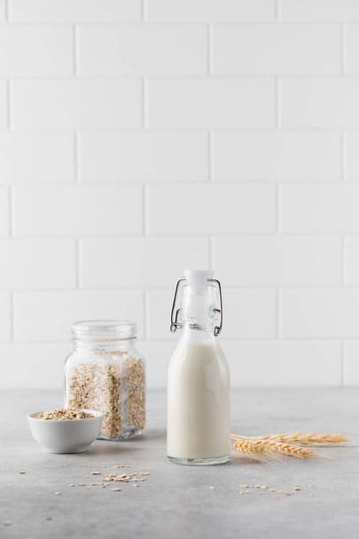 Alternative vegetable milk from oat flakes in a bottle on a light background. Vegetarian milk. - Foto, Imagen