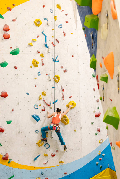 Young Woman rock climbing indoors. - Фото, изображение