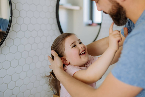 Father checking his daughters teeth in bathroom, morning routine concept. - Fotoğraf, Görsel