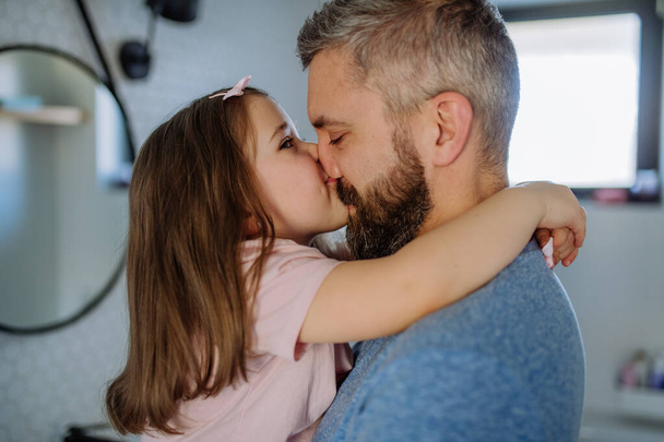 Отец целует свою маленькую дочь в ванной. - Фото, изображение