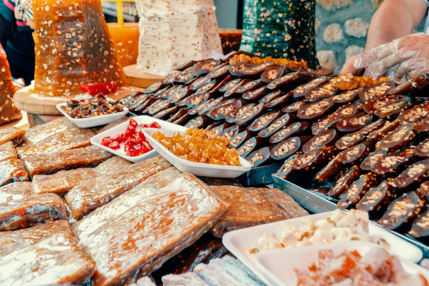 Traditional famous Turkish sweet Walnut Sausage | Cevizli sucuk and Paste with walnut  |  Cevizli pestil on a showcase in a food shop in bazaar. Turkish dried fruit pulp with walnut - Foto, Imagen
