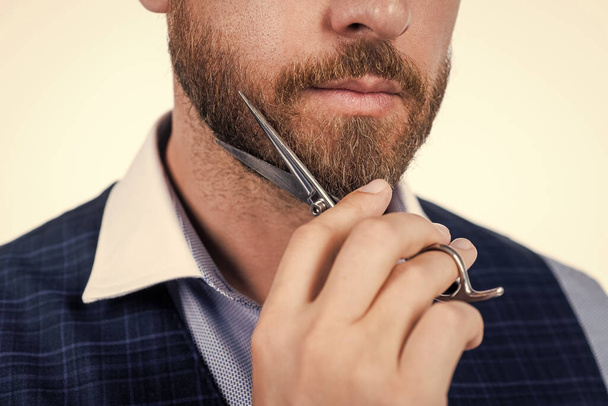 cropped bearded man cut his beard with barber scissors, barbering - Foto, afbeelding