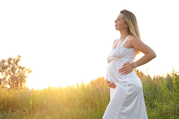 屋外妊娠の肖像画:美しい若い妊婦は子供を期待し、自然をお楽しみください。幸せな未来の母親はすぐに赤ちゃんを期待して. - 写真・画像