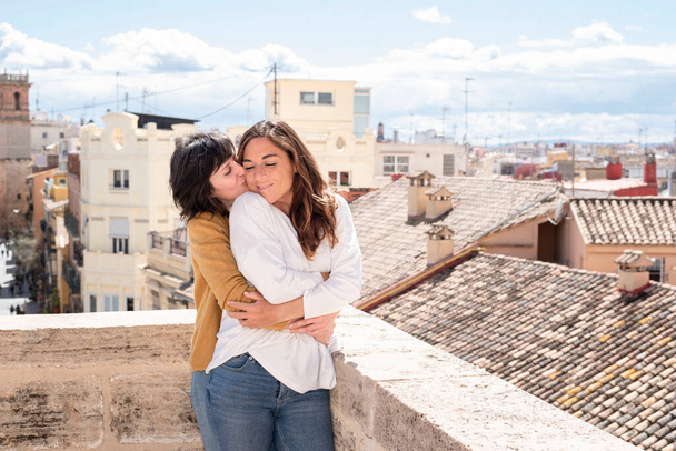 lesbian couple hugging on rooftop with city view - Foto, imagen
