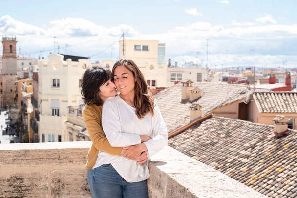 lesbian couple hugging on rooftop with city view - Foto, imagen