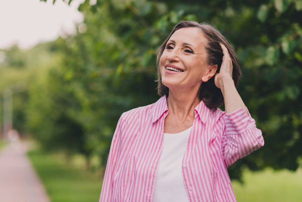 Photo of dreamy sweet retired woman dressed striped shirt enjoying good weather arm head outside countryside landscape - Zdjęcie, obraz