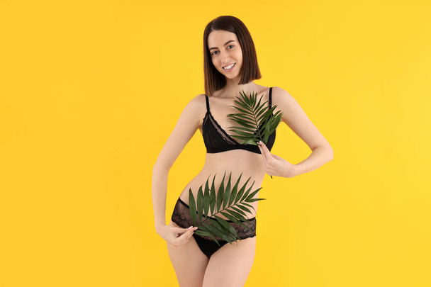 Attractive young woman in underwear on yellow background - Fotó, kép