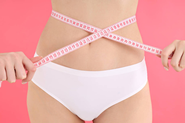 Concept of weight loss, young woman on pink background - Фото, зображення